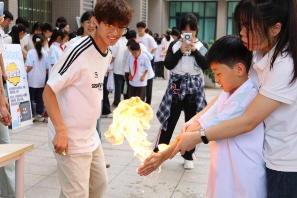 小朋友们在室外广场体验“火焰掌”实验。重庆师范大学供图 小朋友们在室外广场体验“火焰掌”实验。重庆师范大学供图